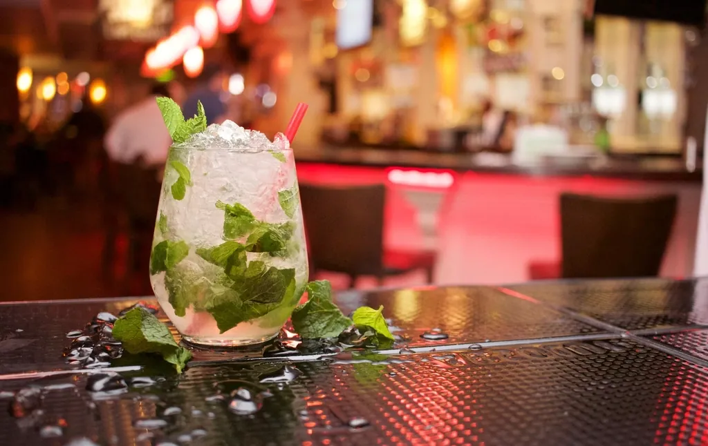 Een mojito met verse munt op een bar in warm avondlicht